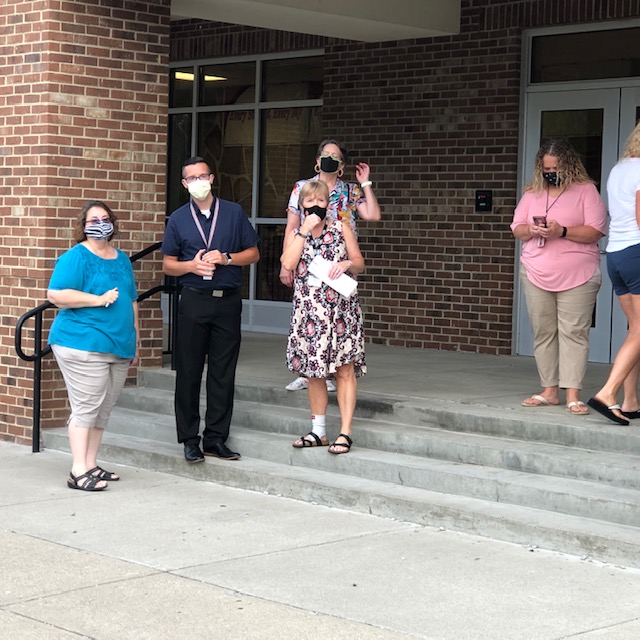 Masked teachers stand outside, waiting for masked students on the first day of school. The mask mandate by the governor had been launched the day before school started, and the KBE added its force to it the day after, on August 12.