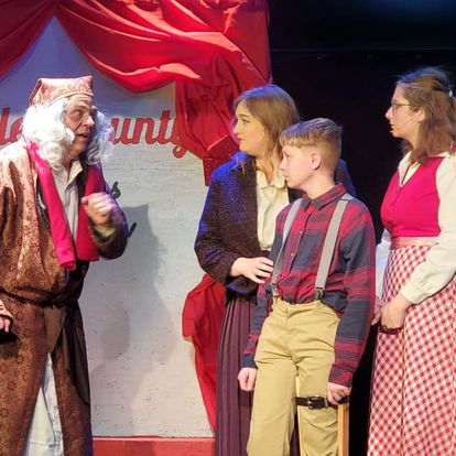 From left: Eb Scrooge, played by Donald Knox; Bobby Jo Cratchit, played by Bethany English; Tim Cratchit, played by Carson Kelsch; and Jane Cratchit, played by Willow Williams