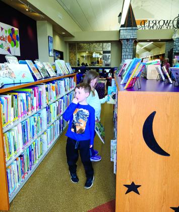 Cooper Courts, 5, and his sister, Carson, 6, look for books in the children’s department. The Courts family, of Falmouth, were in the habit of visiting the library weekly and said they are glad to be back.