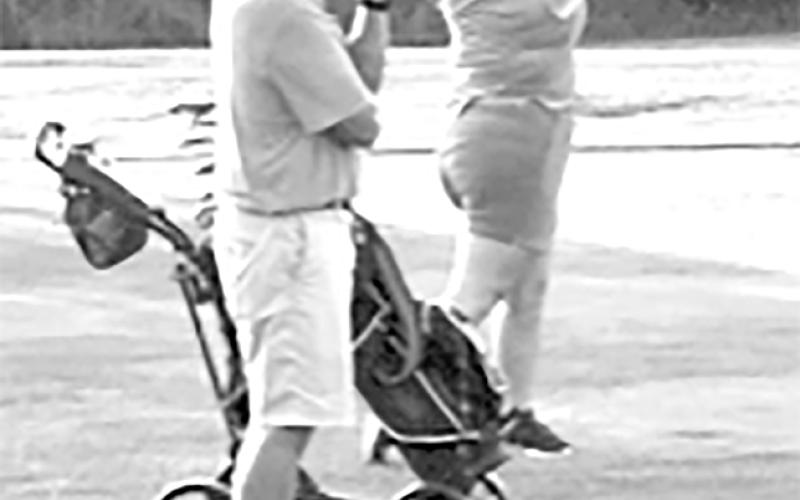 Coach Rob Bertram watches Stormy Ward tee off