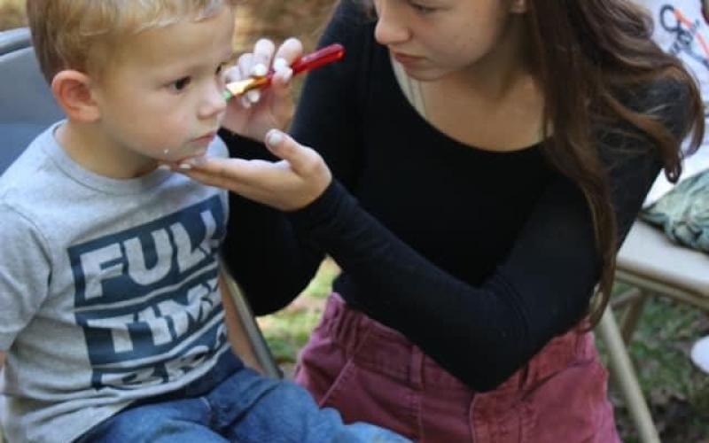 Emma Gillespie paints the face of a little guy. Face painting is always a popular attraction.
