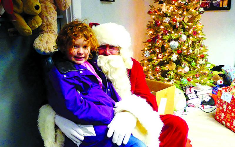 Santa listens to a young lady give her wish list as dozens wait for the opportunity. Gifts were piled high in the area, and Kelly Mosley said enough came that she had to make a run to Santa’s workshop to get more.