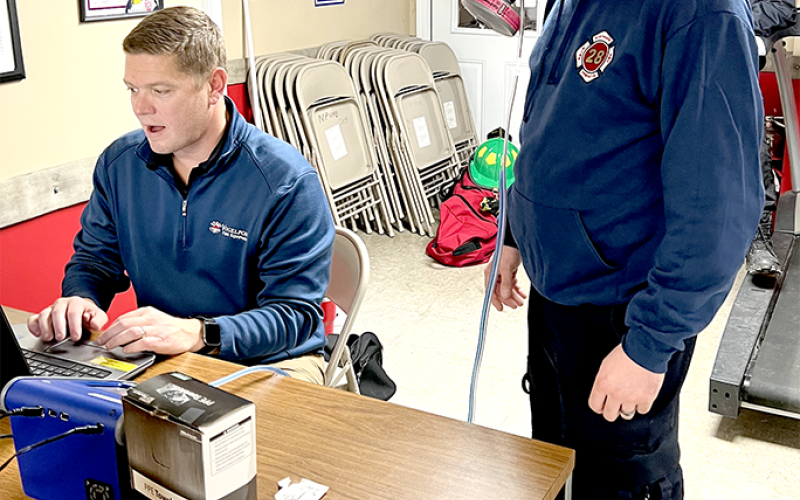 NPFD volunteer firefighter Josh Seitz gets fitted for a mask while sales representative Adam Bowsher inputs information into a database and makes adjustments.