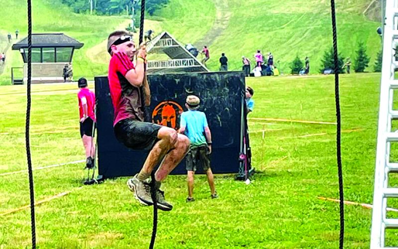 Levi Wolfe attempting to climb a slippery rope to ring the bell at the top