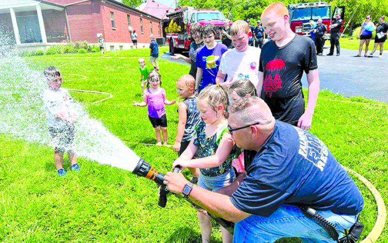 Asst. Fire Chief Travis Reis allows children to help with the hose as others have fun in the spray.