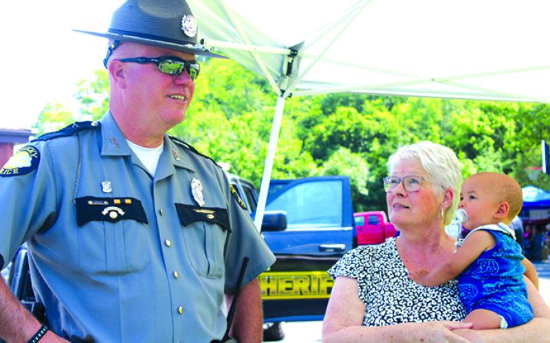 KSP Trooper David Jones talks with Juanita Hughes, holding  Myles, as her granddaughter takes pictures and her other grandson takes advantage of the fun.