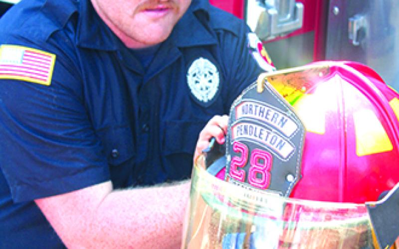 A tyke tries on a fire helmet from Northern Pendleton Fire Department.