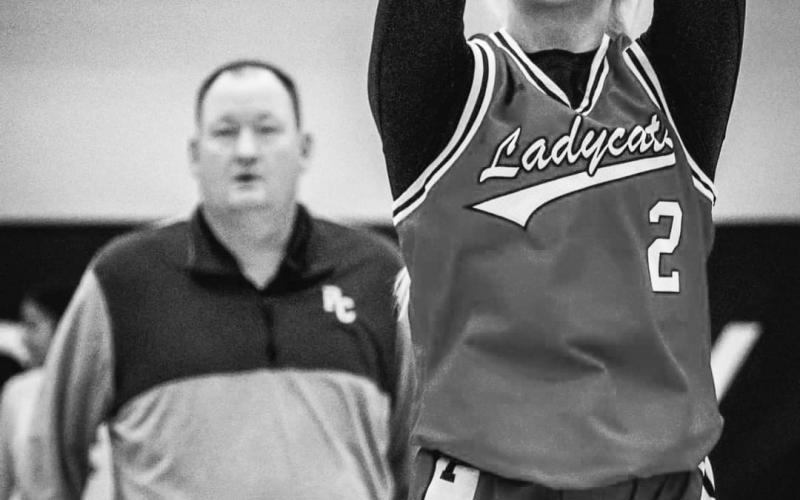 Ladycats sophomore Lilly Ashcraft follows through on her free throw attempt while team head coach Patrick Kelsch looks on. Photo by Pete Wigginton.