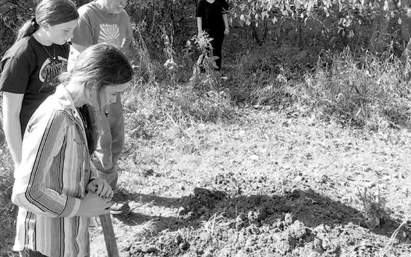 Barth Johnson shows students how to break up the soil in one of the 10-foot plots on SMS's nature trail.