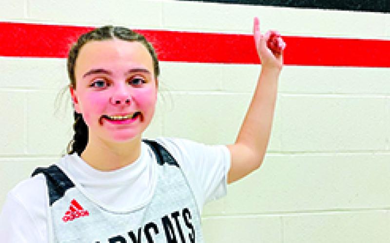 Kathy Yelton's great-niece and current Ladycats player Lilly Brown proudly wears her aunt's basketball number and points to a plaque bearing Yelton's name. Yelton helped coach Lilly and other girls for many years. Yelton passed away from breast cancer in 2021.