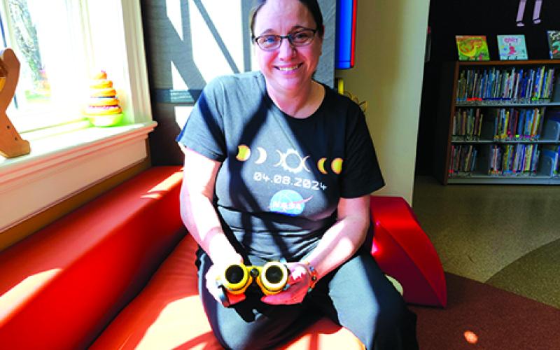 Pendleton County Public Library Programming Assistant Hannah Pearson holds a pair of Sunoculars, which appear to have black lenses. They are heavily filtered to allow the person using them to look directly at the sun. Photo by Burton Cole.