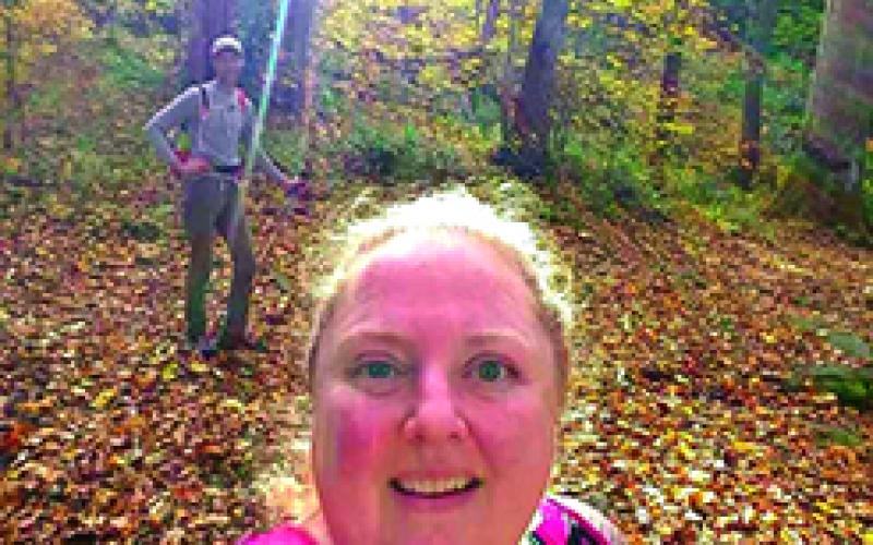 McElfresh and her husband, Tim Richmond, background, hike in the woods.