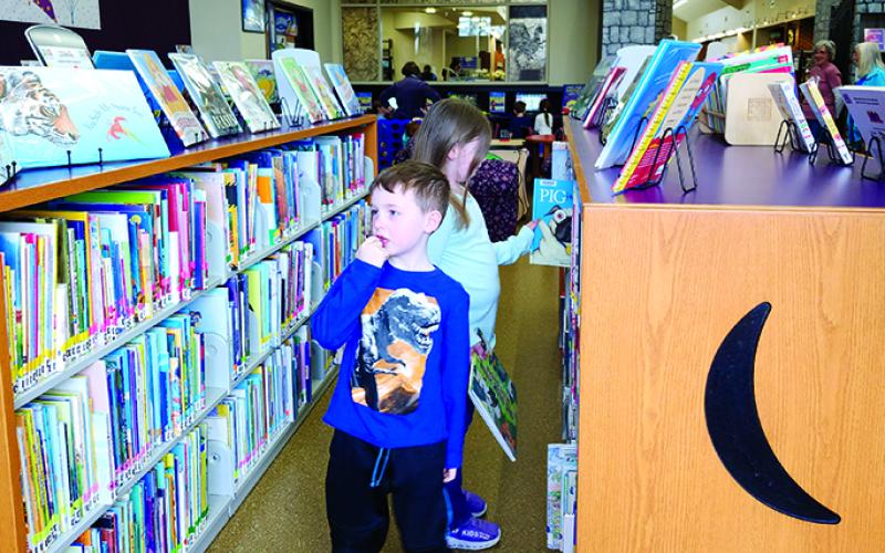 Cooper Courts, 5, and his sister, Carson, 6, look for books in the children’s department. The Courts family, of Falmouth, were in the habit of visiting the library weekly and said they are glad to be back.