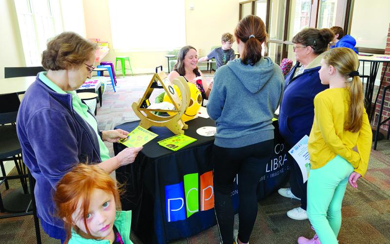 Pendleton County Public Library Programming Assistant Hannah Pearson, center, behind table, shows the library's solar eclipse equipment and studies at the entrance of the library's new teen space. Photos by Burton Cole.