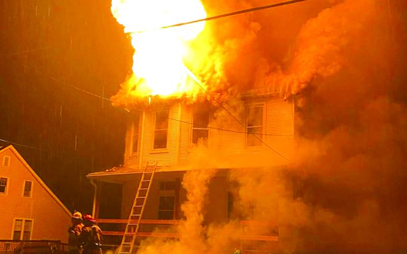 Flames shoot from the top of the Pettit home, 503 Maple Ave., Falmouth, in the early hours of April 30. Resident Bob Pettit, a retired firefighter and city councilman, said smoke detectors woke him and his wife, saving their lives. Photo by Kelly Braa.