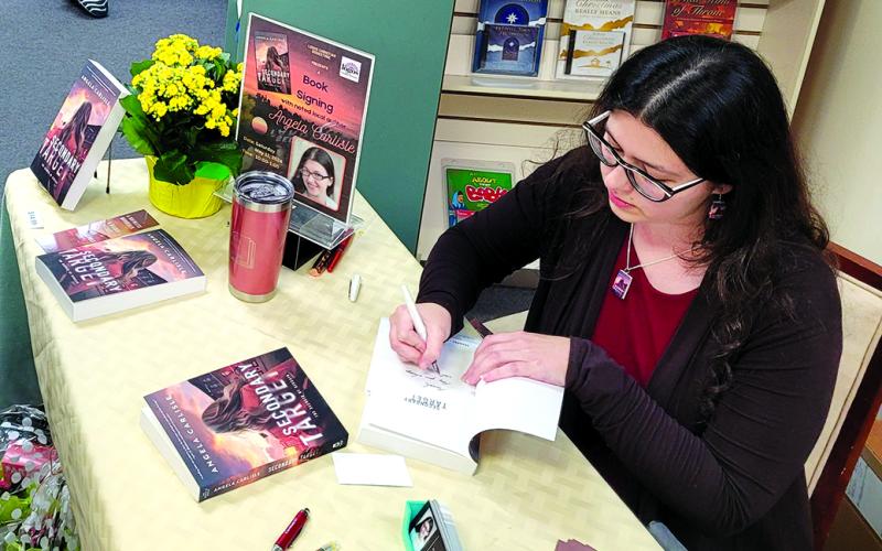 Angela Carlisle of DeMossville signs copies of her novel “Secondary Target,” which is set in Pendleton County, at at Logos Christian Bookstore in Alexandria. Photo courtesy of Angela Carlisle.