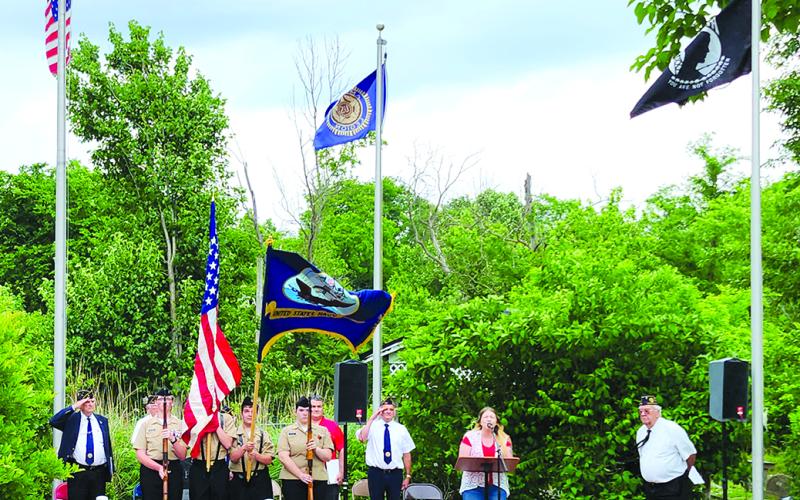Kellie Daugherty, at the microphone, sings “The Star-Spangled Banner.” Navy Junior Reserve Officers Training Corps cadets, from left, Tanner Morris, Micah Seksay, Brian Lynch and Emmalissa Brown present the colors during the national anthem. Post members in the background include Donald Wells, left, Gary Barnard, between the cadets and Daugherty, and Post Commander Jim Sharp, right.