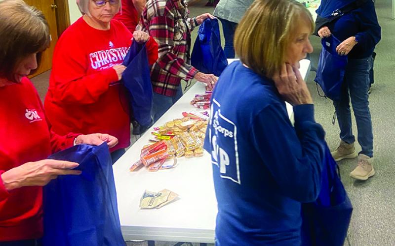 Pendleton County RSVP volunteers stuff canvas bags with snacks and warm clothing to be distributed to the county’s homeless population. Photo courtesy of RSVP.