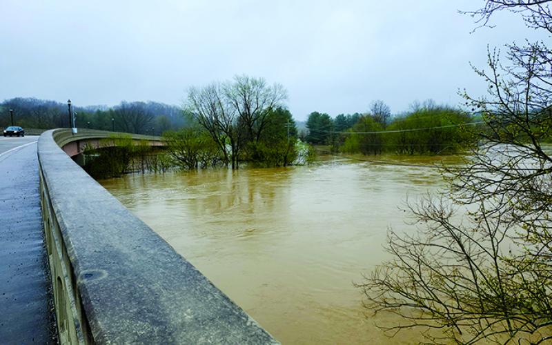 Rising, muddy water rushes beneath the bridge on Highway 22 in Falmouth. Photo by Burton Cole.