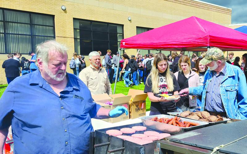 Masons Larry York, left, Dwaine Smith and RC Cooper serve hamburgers in hot dogs members of the Pendleton County High School Class of 2025 on Thursday outside the school. Hidden by the line of seniors is Mason Kenny Hale. Commencement ceremonies were held the following day. This is the sixth year that the De Moss Lodge 220 of the Free and Accepted Masons have put a cookout for graduating seniors on their last day of school.