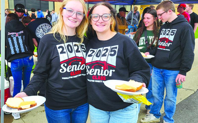 Graduating seniors Maddie Marshall, left, and Lily Gibson have their plates ready as the line inches toward the grill.  Photos by Burton Cole.