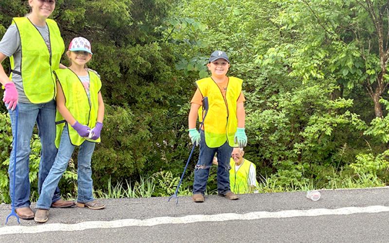 Alison Moore, left, daughter Ava Moore and son Wyatt Moore clean along a roadway in Butler, with Patrick Clore in the background, during the First Annual Boo Project River Sweep and Roadside Cleanup. Photo by Mason Taylor.