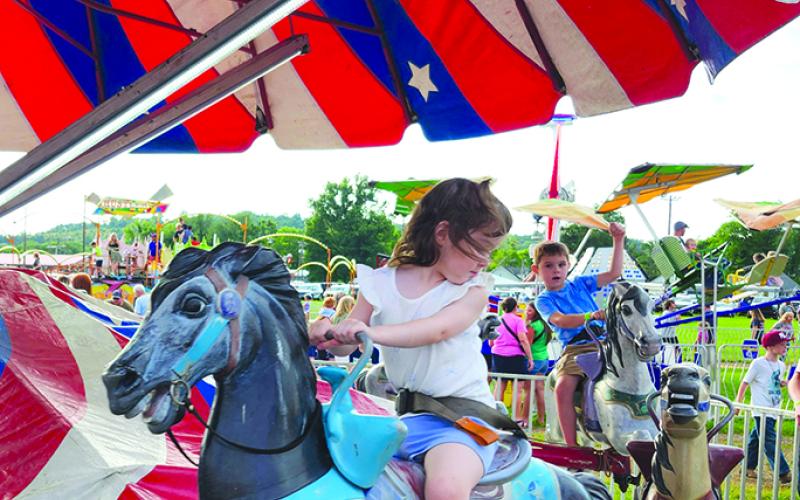 Lillie Merrill, 3, and her brother, Benton Merrill, 6, of Falmouth ride the merry-go-round. Photo by Burton Cole.