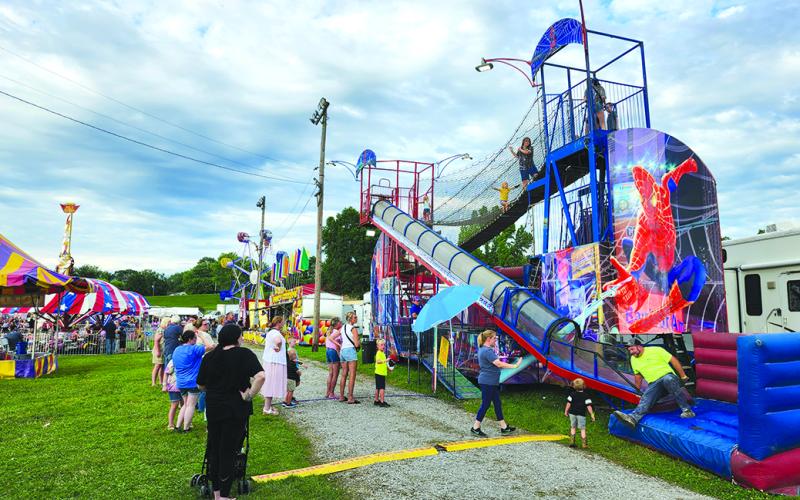 Kids big and small lined up for rides, slides and the fun house thrills. Photo by Burton Cole.