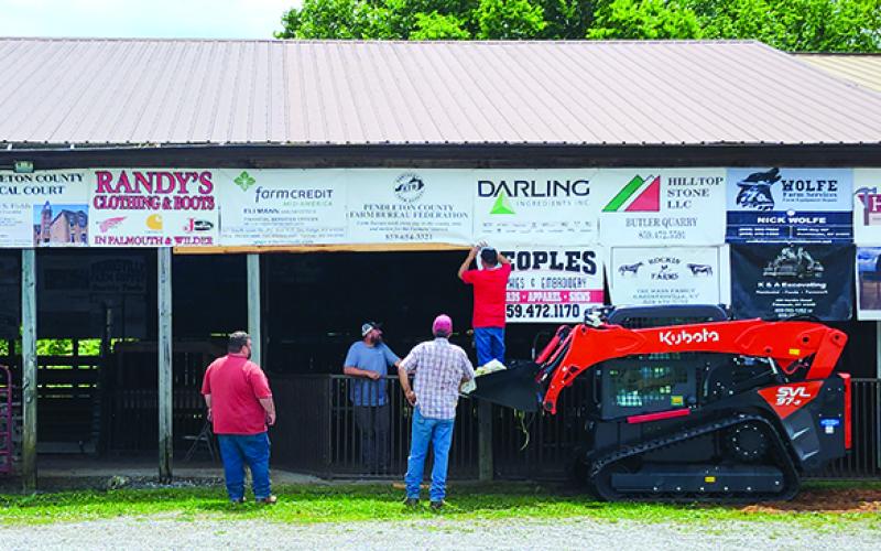 Crews hang signs on the livestock barn and show ring. Photos by Burton Cole.