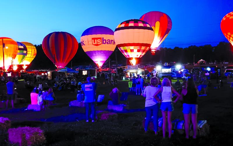The feels-like heat values continue to top 100 degrees in Northern Kentucky, but that didn’t stop people from turning out festivals and events in Pendleton County. Two of them included the second annual Balloons and Tunes on Saturday at the Kentucky Wool Festival Grounds, above. This photo shows some of the 10 grounded hot air balloons that were lit up at dusk for a balloon glow. The family-oriented event also included bands, food trucks and a kids play area. Photo by Sam McClanahan.