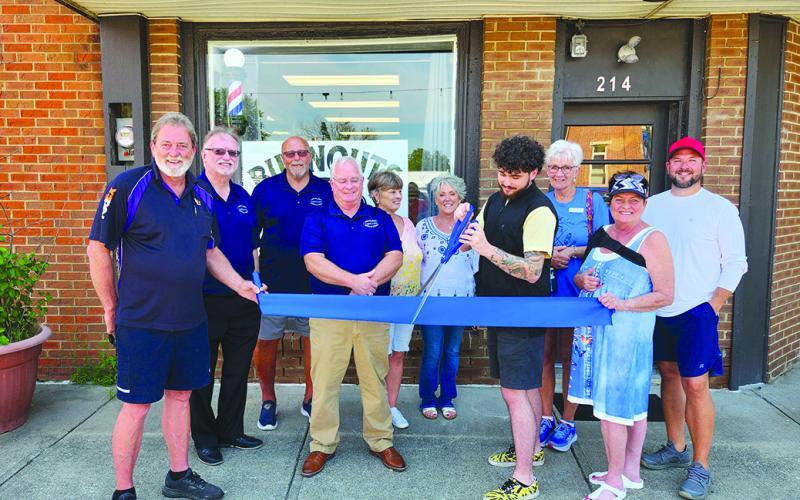 Joining Garrad Dennie for the official ribbon-cutting July 25 for Burnouts Barber Shop in Falmouth are, from left, his dad Gary Dennie, Pendleton County Chamber of Commerce Vice President Neil Belcher, Chamber member Randy Wells, Chamber President Gary Hicks, family friend Dixie Wells, Pendleton County Director of Economic and Tourism Development Tami Vater, Garrad Dennie, family friend Kim King, mom Dina Dennie and brother Josh Plummer. Photo by Burton Cole.