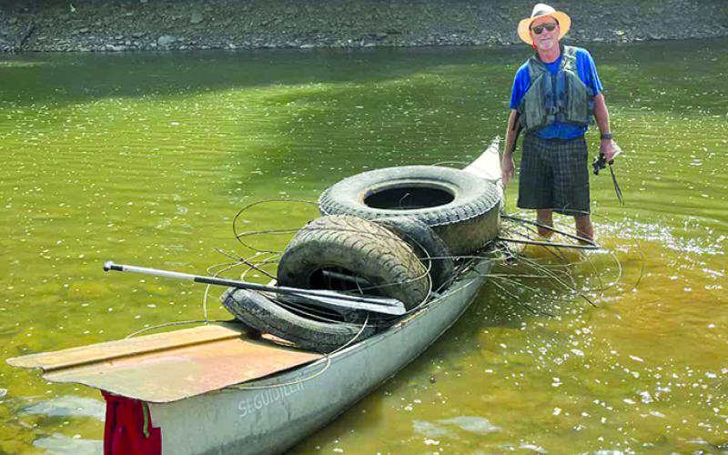 Miller poses with a partial load of trash and tires on his canoe on the Licking River.