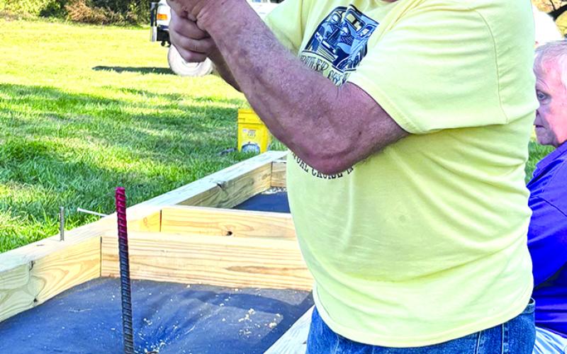 Herman Schack pounds a stake into one of the 6-by-6 timbers framing the new stone pathway.