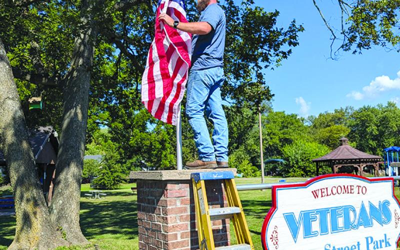 Joseph Williams hangs a new flag at  Veterans Park in Falmouth