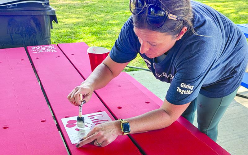 Falmouth Mayor Sabrina Hazen stencils inspirational sayings on freshly painted tables at the park