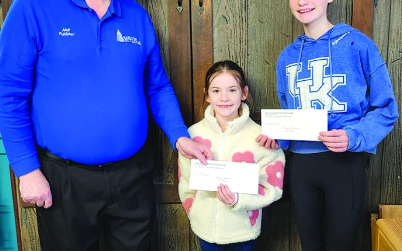 Outlook publisher Neil Belcher, left, hands the first place prize of $25 to Evelyn Bachman, 7, of California, Kentucky. At right is her sister, Lilian Bachman, 12, who received $10 for second place.