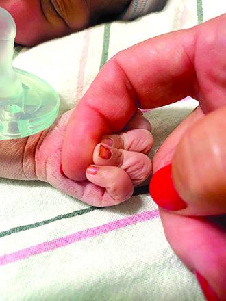A newborn dropped off at a Carmel, IN, Safe Haven Box grips the finger of her rescuer. The baby is now a year old and is in a loving family. Photo courtesy of Safe Haven Baby Boxes, the non-profit organization responsible for fundraising for box installation.