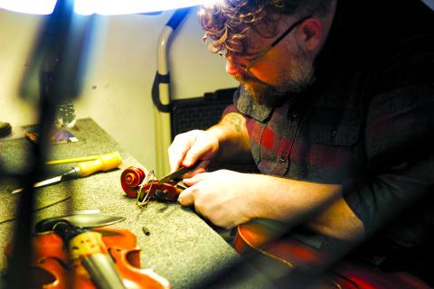 2005 Pendleton County High School graduate Brandon Godman repairs a violin in his shop, The Fiddle Mercantile, in San Francisco. Both a businessman and a recording artist who splits his time between San Francisco and Nashville, Godman said his latest solo album, “I Heard the Morgan Bell,” is his tribute to “back home.” Photo provided by Brandon Godman. 