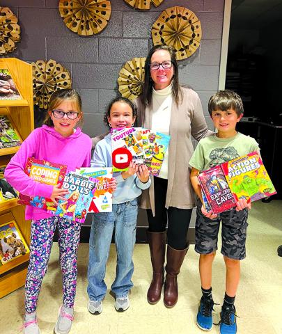 Northern Elementary School third-graders Lucy McCain, Monroe Johnson, media specialist Tina Record, and Jacob Hegyi show off some of the 100 books donated to the school by the newly opened Dollar General store in Butler. Photo by Nila Harris.
