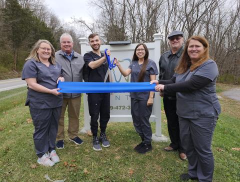 Cutting the ribbon to officially open Riverside Dental with its new dentist are, from left, Kristen Holbrook, dental assistant; Gary Hicks, president, Pendleton County Chamber of Commerce; Dr. Christian Zint, dentist; Maggie Thomas, front office staff and Zint’s wife; Neil Belcher, Chamber vice president; and Tammy Wessel, front office manager. Zint opened the office Dec. 2, and succeeds retired dentist Dr. Monte McElfresh. Photo by Burton Cole.