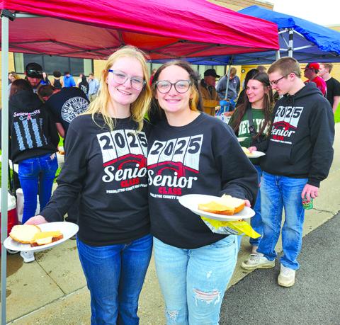 Graduating seniors Maddie Marshall, left, and Lily Gibson have their plates ready as the line inches toward the grill.  Photos by Burton Cole.