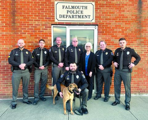 The Falmouth Police Department is, back row from left, Sgt. Broderick Schmeing, Officer Jonathon Bayless, Assistant Chief Nicholas Timon, Chief Marty Hart, office manager Marilyn Belcher, Sgt. Ken Hall and Officer Matthew Campbell. Kneeling is former K-9 Officer Kyle Florer with Cairo.