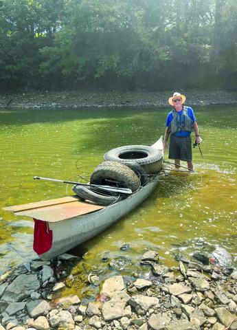 Miller poses with a partial load of trash and tires on his canoe on the Licking River.