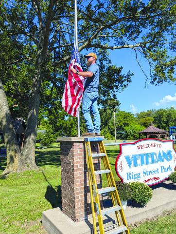 Joseph Williams hangs a new flag at  Veterans Park in Falmouth