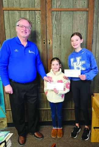  Outlook publisher Neil Belcher, left, hands the first place prize of $25 to Evelyn Bachman, 7, of California, Kentucky. At right is her sister, Lilian Bachman, 12, who received $10 for second place.