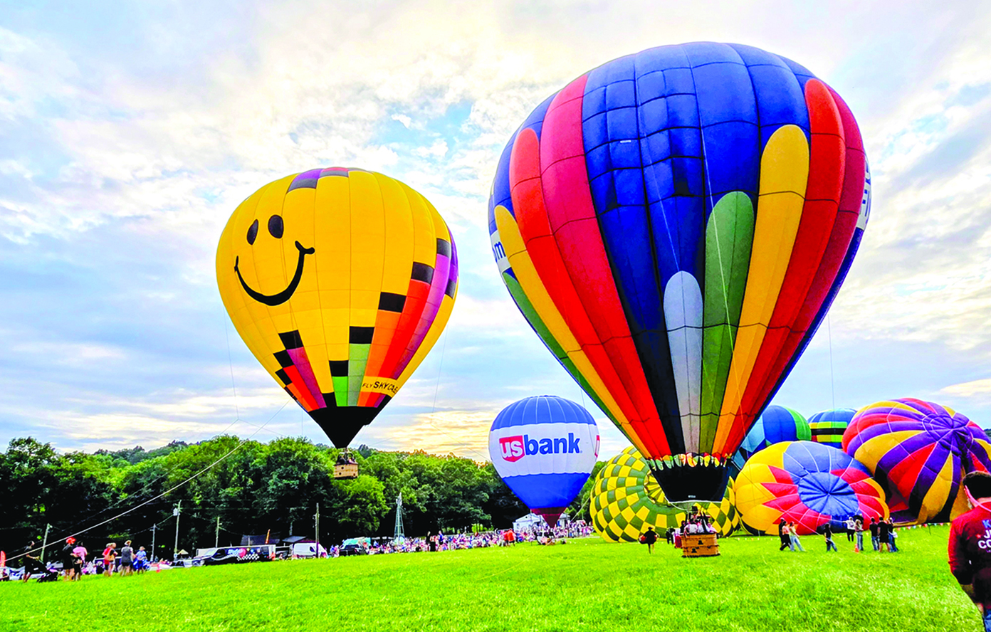 Two tethered balloons offer rides while the grounded balloons begin to inflate.