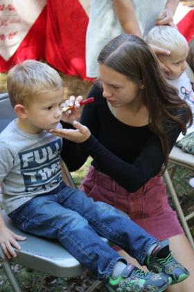 Emma Gillespie paints the face of a little guy. Face painting is always a popular attraction.