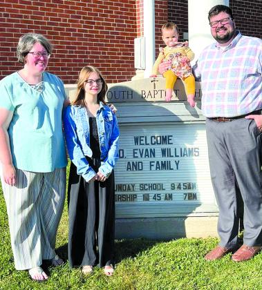 The Williams family stands around the sign that welcomes them. They are now in ministry at Falmouth Baptist Church.