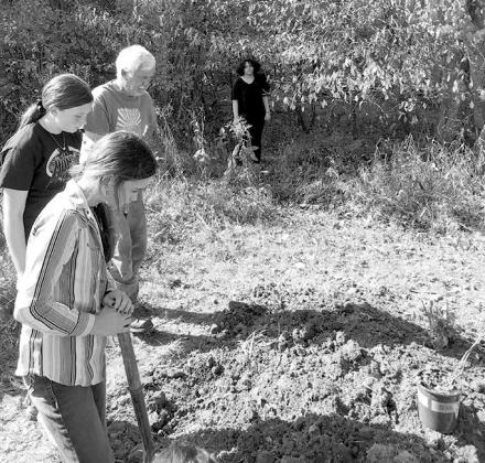 Barth Johnson shows students how to break up the soil in one of the 10-foot plots on SMS's nature trail.