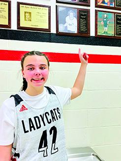 Kathy Yelton's great-niece and current Ladycats player Lilly Brown proudly wears her aunt's basketball number and points to a plaque bearing Yelton's name. Yelton helped coach Lilly and other girls for many years. Yelton passed away from breast cancer in 2021.